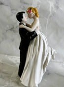 Groom holding up bride ceramic wedding cake topper 