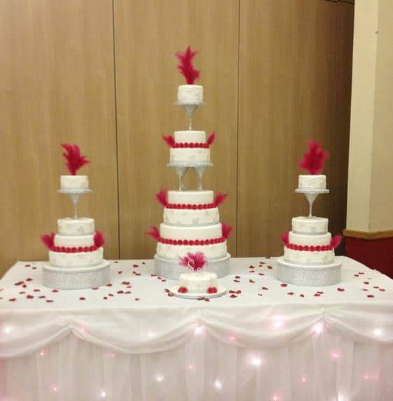 Extra large wedding cake and matching side cakes separated with diamond glasses and feathers on the top