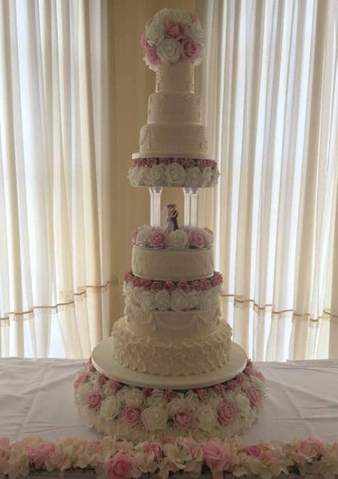 Extra large wedding cake was fine royal icing detail separated pillars for an old walt feeling with sugar and silk flowers
