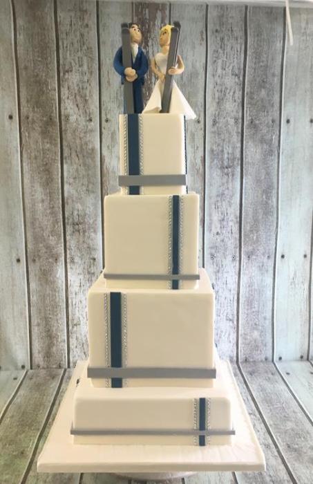Extra large squares wedding cake in a geometric design topped off a wedding cake topper on a handmade bride and groom skiing