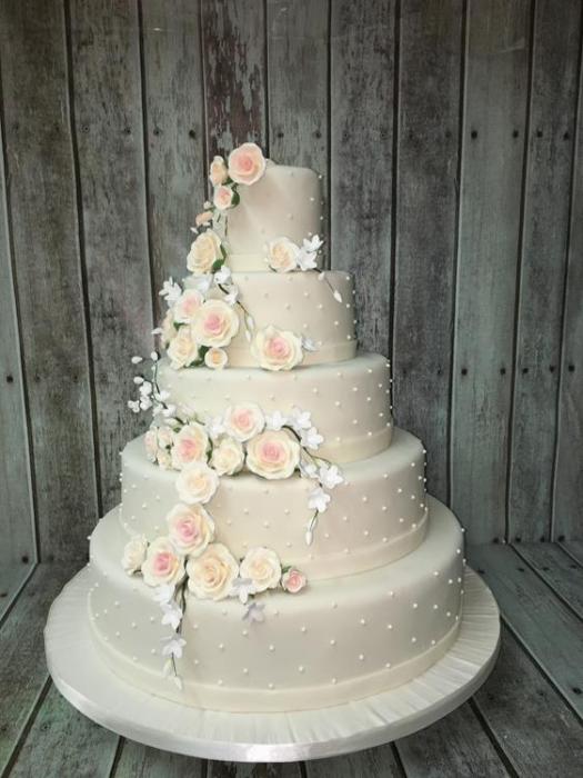 Extra large wedding cake with a cascading of delicate shore flowers and green foliage