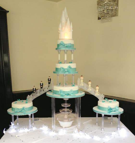 Extra large wedding cake on pillars which bridges and fountains chopped off with a Lighted church