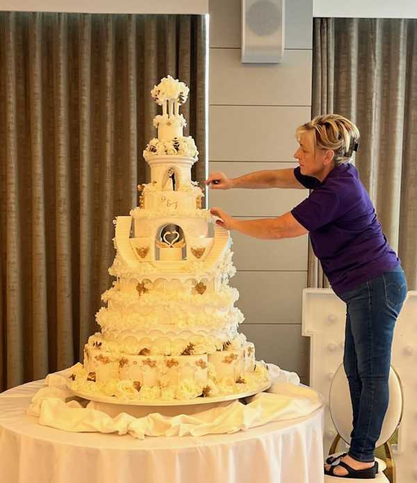 Extra large wedding cake adorned with cherups and gold hand painting sand silk flowers
