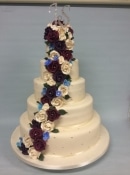 Extra large wedding cake with blue and  burgundy flowers made of sugar and icing  pattern and  diamond initials