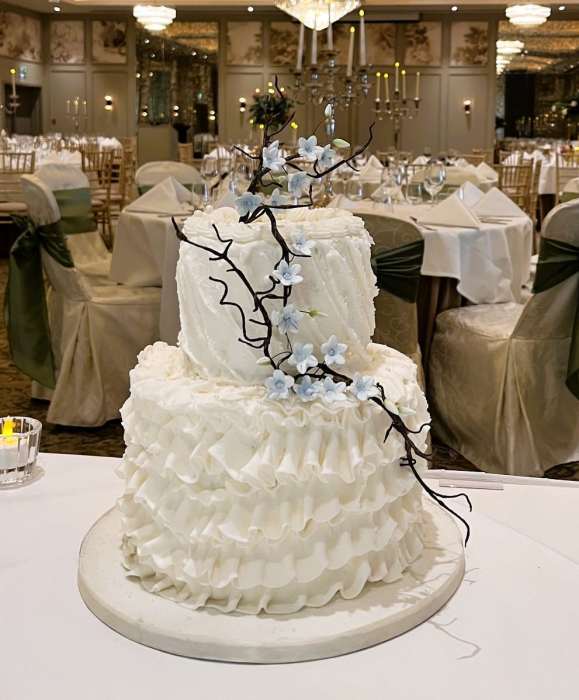 Buttercream-wedding-cake-with-hand-piped-frills-and-Blue-sugar-Jasmine-and-twigs