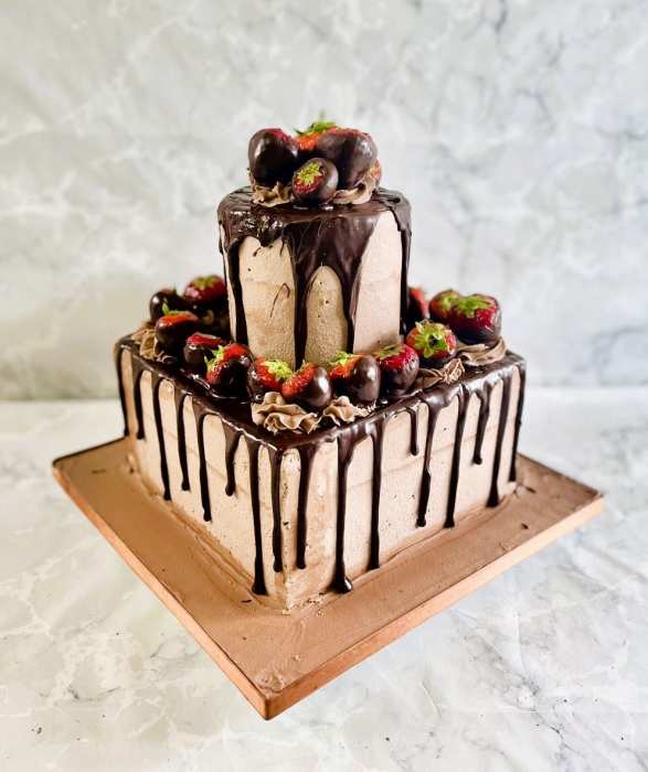 Square buttercream  finish wedding cake with fresh fruit and a chocolate drip