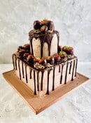 Square buttercream  finish wedding cake with fresh fruit and a chocolate drip 