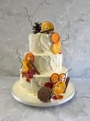 Rustic buttercream cake with fresh dried oranges and sugar autumn leaves