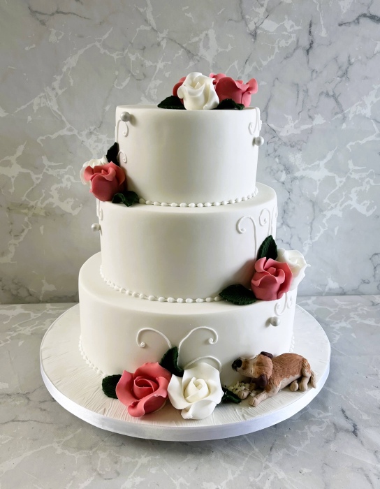 Wedding cake with hand piping and sugar roses with beloved dog eating into the cake