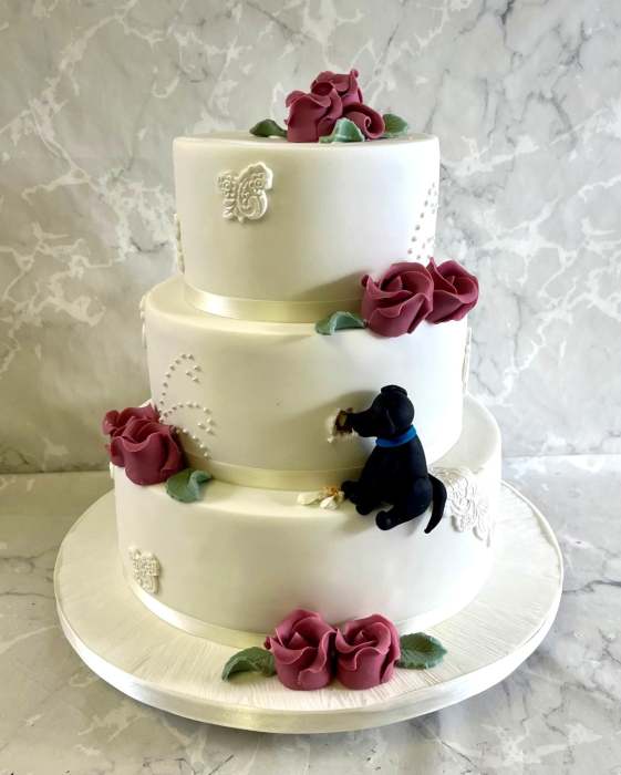 Vintage lace wedding cake with sugar dog eating into the cake