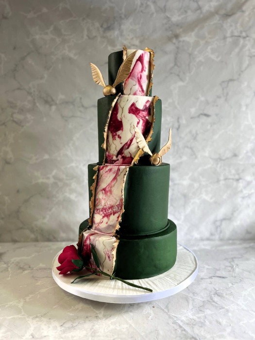 Peeled back Dark green icing revealing Marbling and gold With Harry Potter and Beauty and the Beast hod