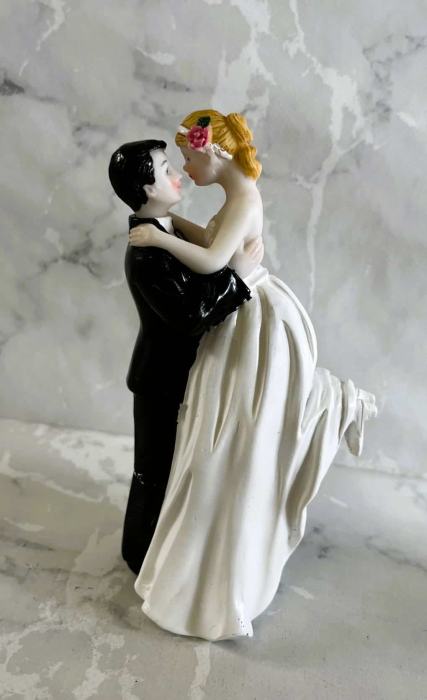 Groom holding up bride ceramic wedding cake topper