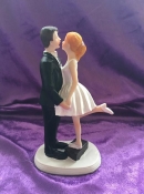 bride standing on suitcase  and groom wedding cake topper