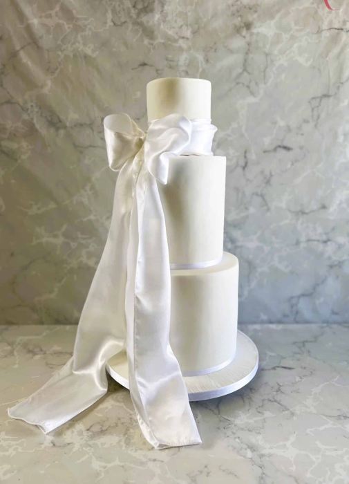 tall slender wedding cake with thick satin draping sash