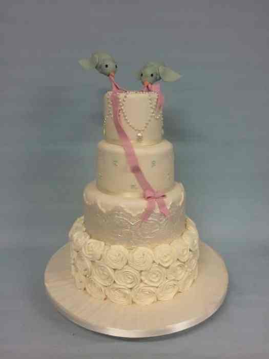 White and pink wedding cake with hand piped rosettes and flying birds