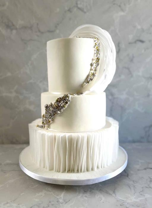 Elegant white wedding cake with wafer paper ruffles and edible pearl decoration