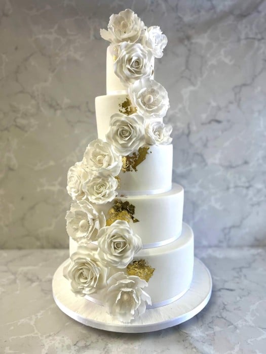 Tall elegant wedding cake with gold leaf and sugar flowers