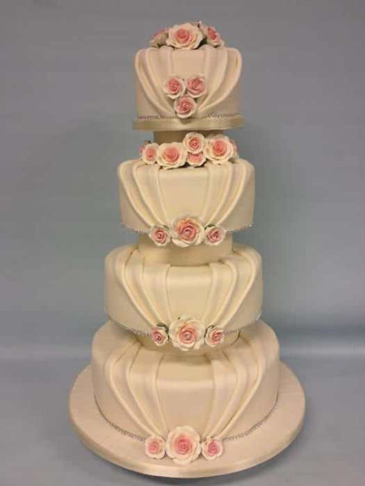 wedding cake with pleated icing and pink flowers
