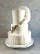 Elegant white wedding cake with wafer paper ruffles and edible pearl decoration 